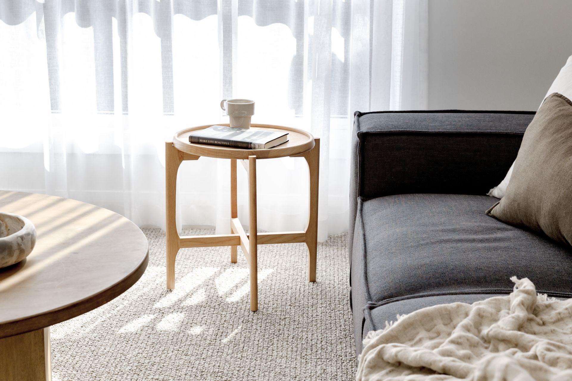 Wooden Side Table With a Book and Mug, Next to a Couch and Round Table in a Bright Room — Evolution Building Group in Dapto, NSW