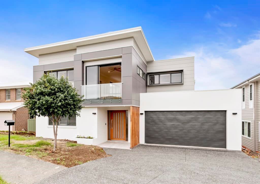 A Modern House with A Large Garage and A Tree in Front of It — Evolution Building Group Dapto, NSW
