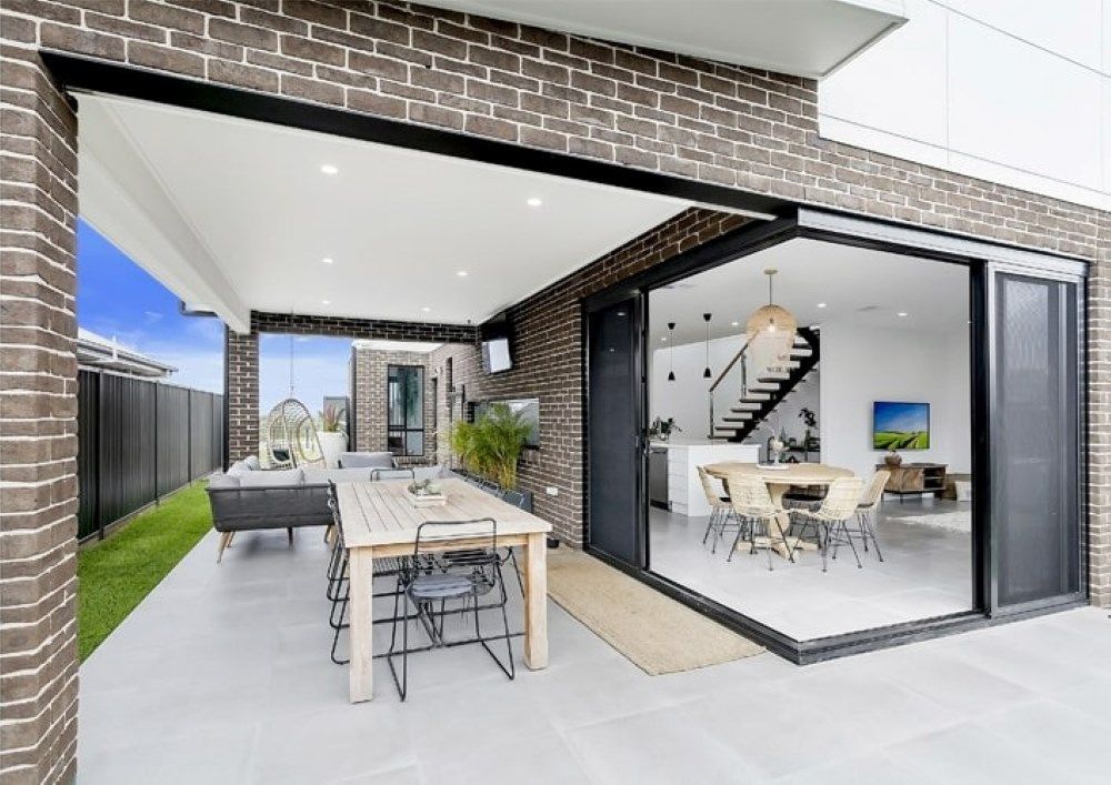 A Large Sliding Glass Door Opens to A Patio with A Table and Chairs — Evolution Building Group Dapto, NSW