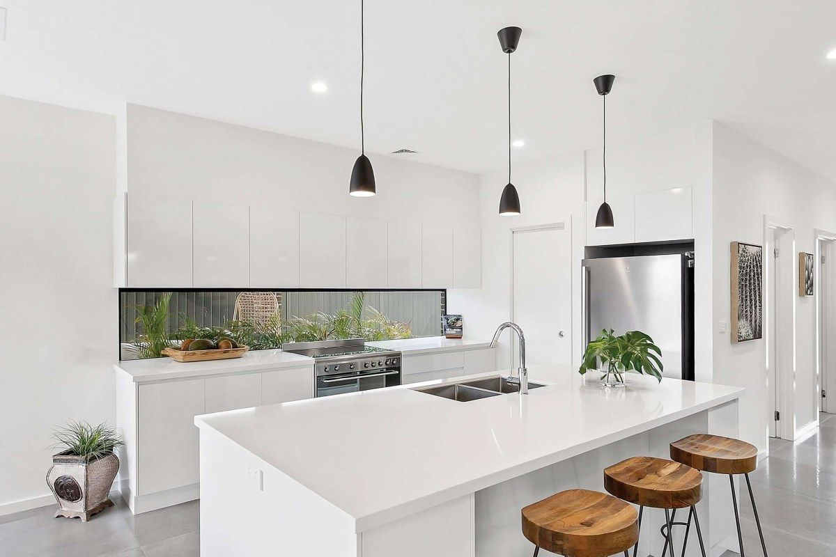 A Kitchen with White Cabinets, a Large Island, and Wooden Stools — Evolution Building Group Dapto, NSW