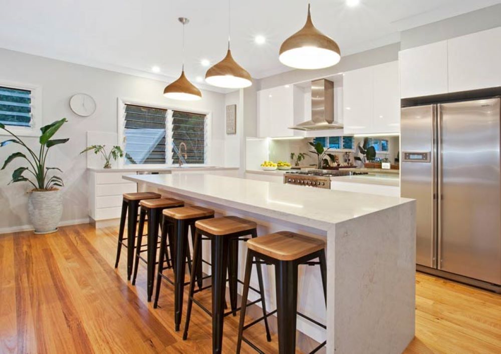 A Kitchen with A Long Island and Stools and A Stainless Steel Refrigerator — Evolution Building Group Dapto, NSW