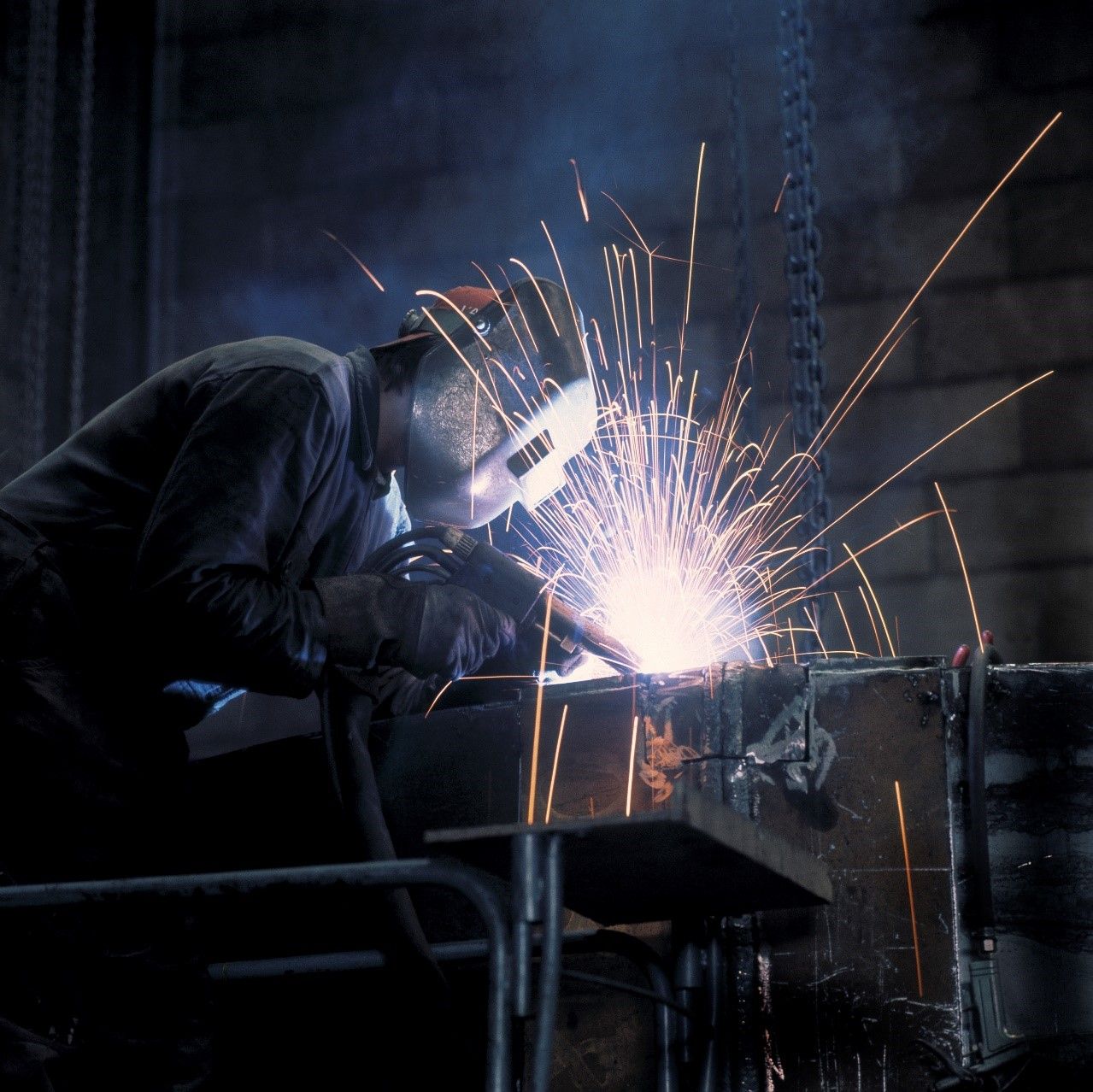 A Man Wearing a Welding Mask Is Welding a Piece of Metal