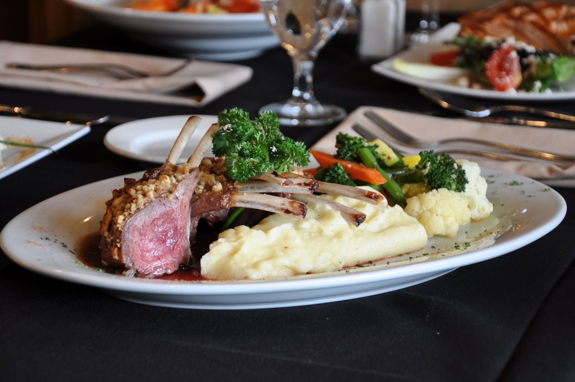 A plate of lamb chops with mashed potatoes and vegetables on a table