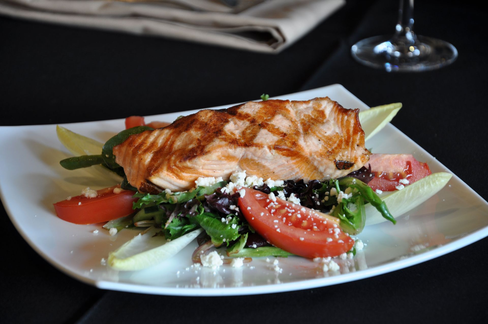 A white plate topped with a piece of grilled salmon and a salad