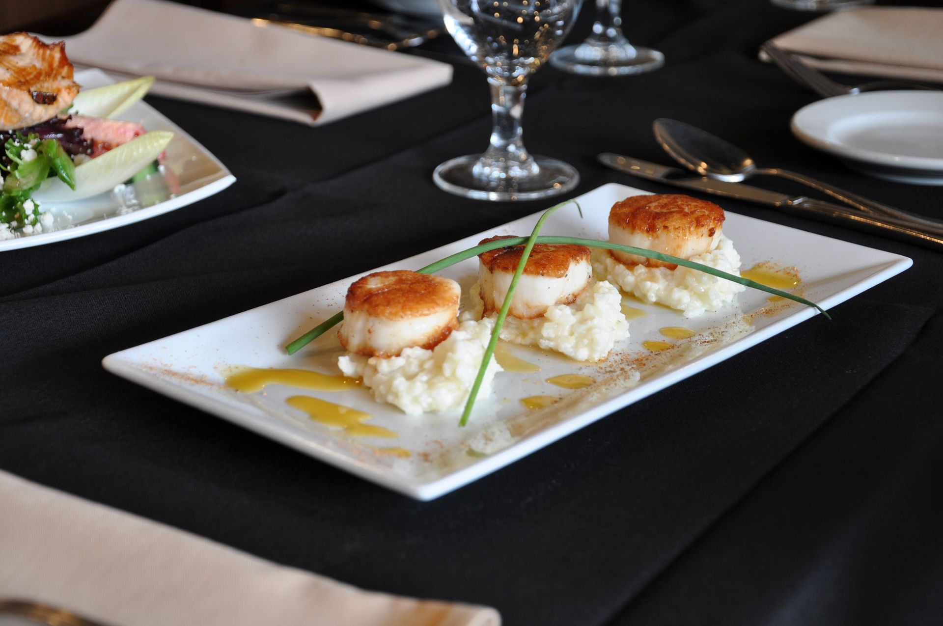 A plate of food with scallops and mashed potatoes on a table.