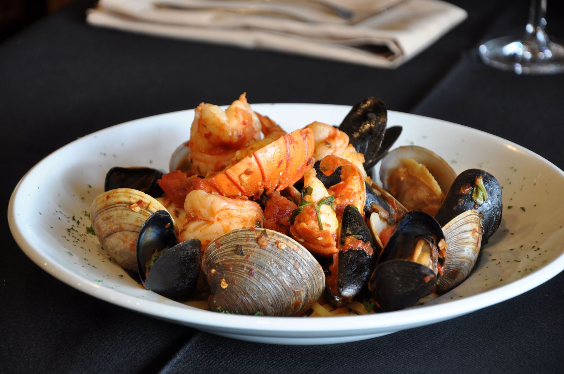 A plate of seafood including shrimp mussels and clams on a table