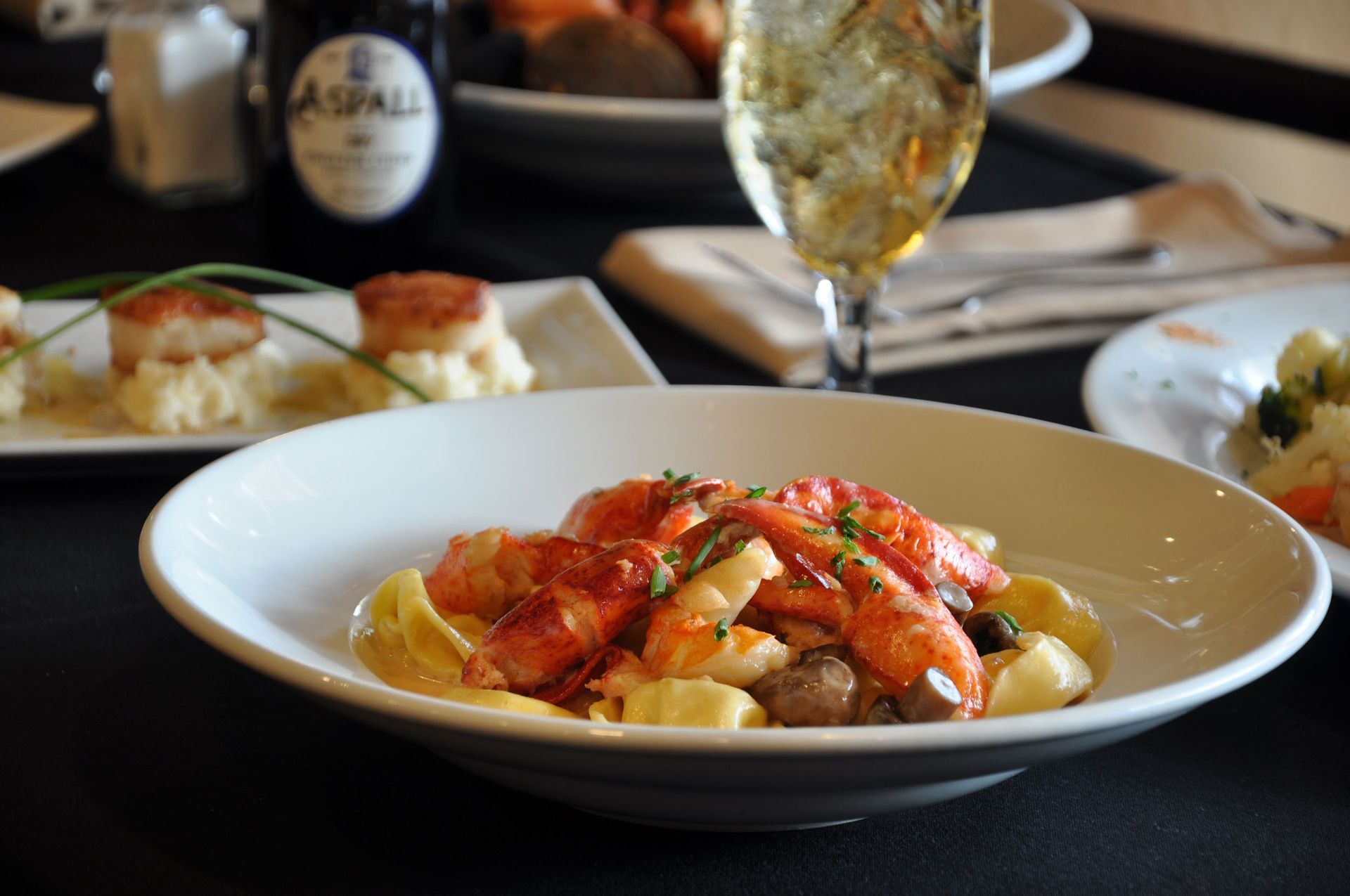 A plate of food on a table next to a glass of wine