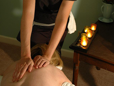 A woman is getting a massage with candles in the background