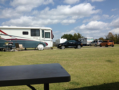 A rv parked in a grassy field next to a picnic table