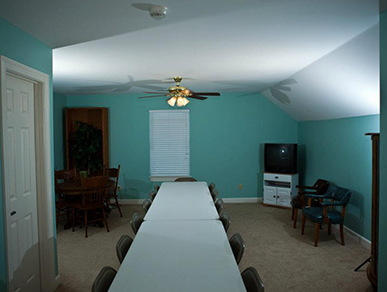 A room with a long table and chairs and a television