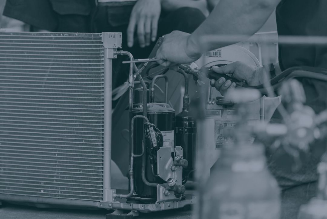 A black and white photo of a man working on an air conditioner.