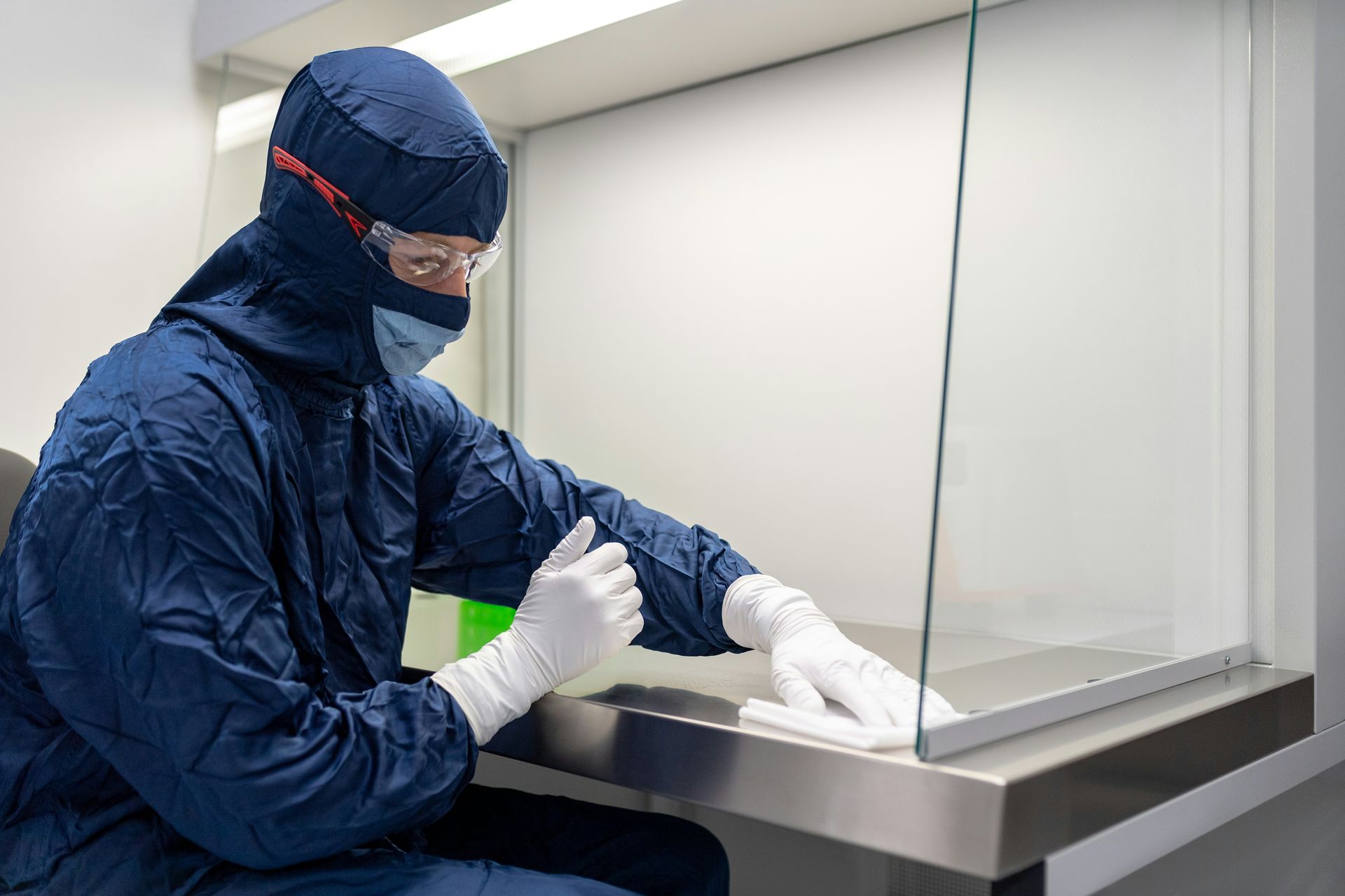 A man in a protective suit is sitting at a table in a clean room.