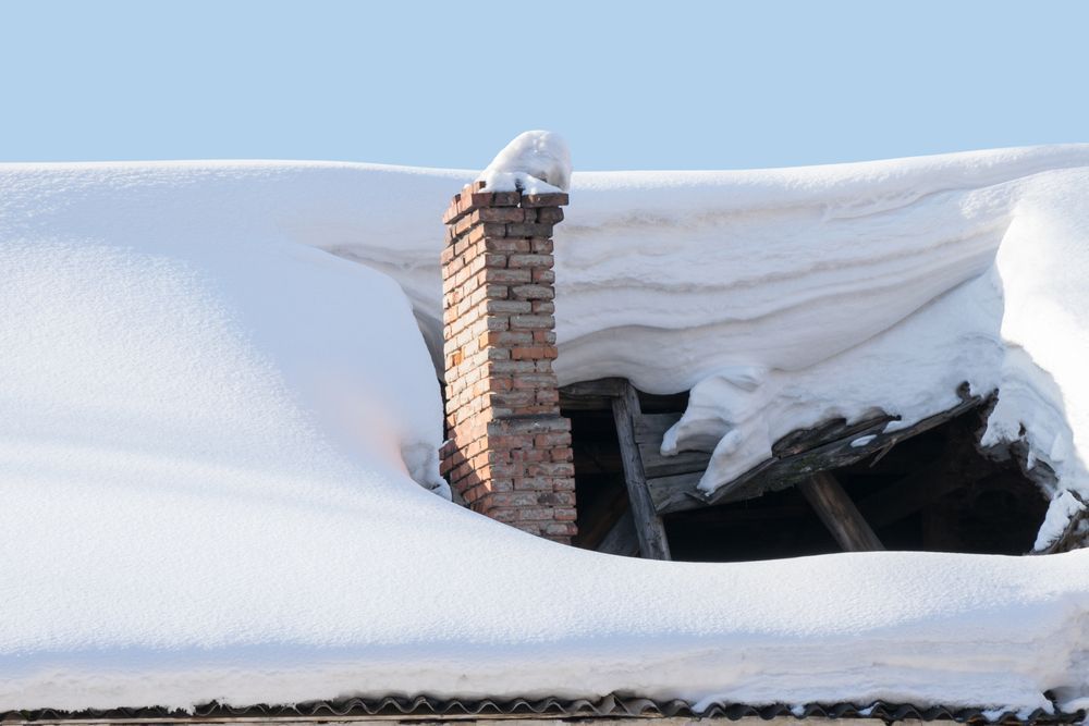 Snow-covered roof with a brick chimney and a large collapsed opening exposing the dark interior
