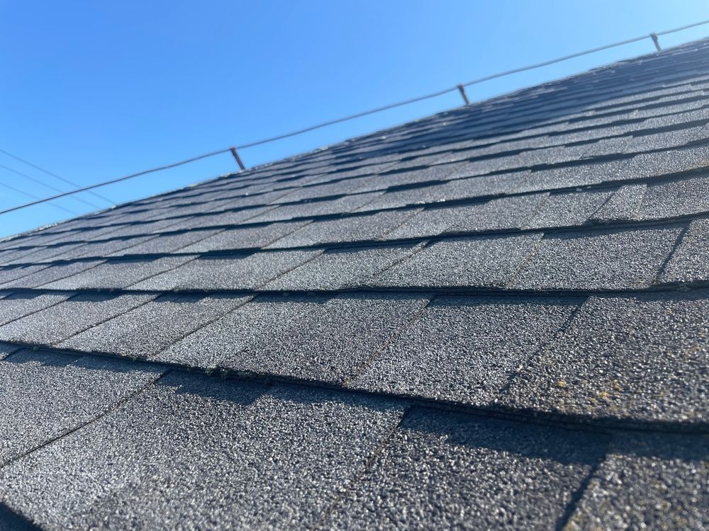 Close-up of a gray shingled roof under a clear blue sky