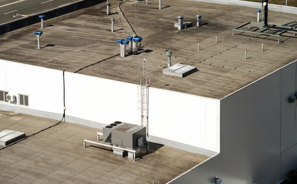 Aerial view of a large white industrial building with rooftop vents and HVAC units.