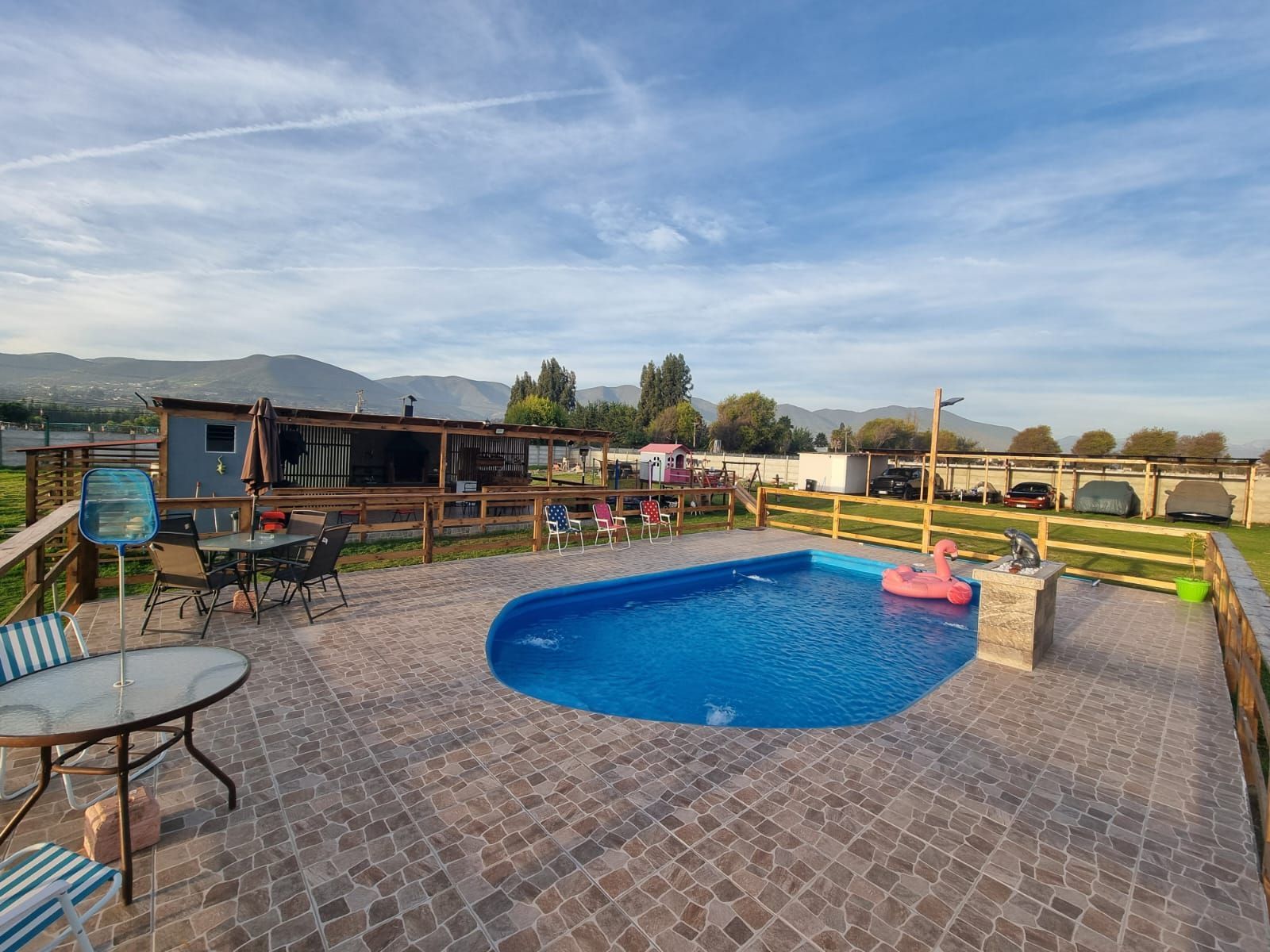 Hay una gran piscina en el patio trasero con mesa y sillas.