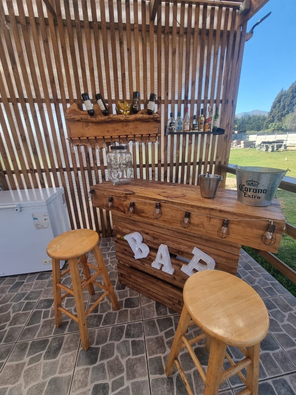 Una barra de madera con dos taburetes y botellas.