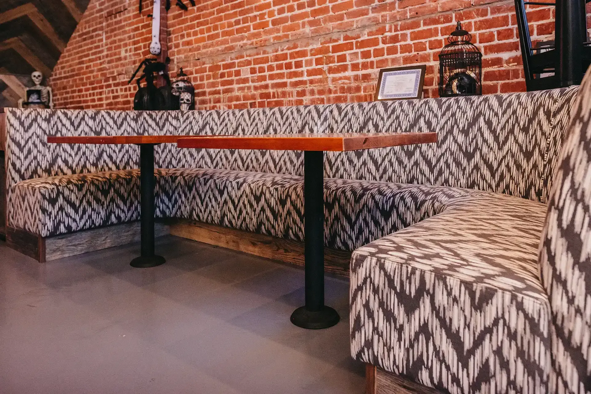 A restaurant booth with tables and chairs in front of a brick wall.