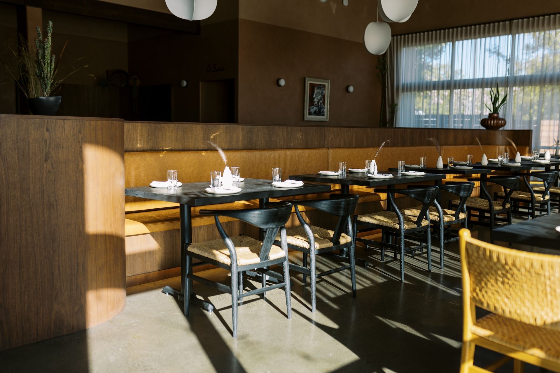 A restaurant with tables and chairs and a large window.