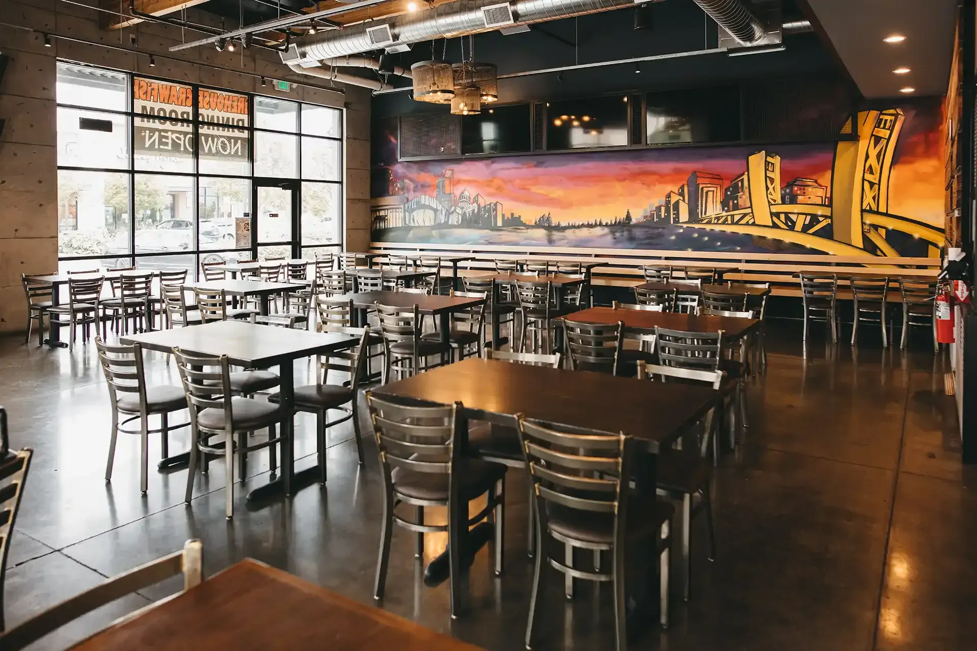 A restaurant with tables and chairs and a mural on the wall.