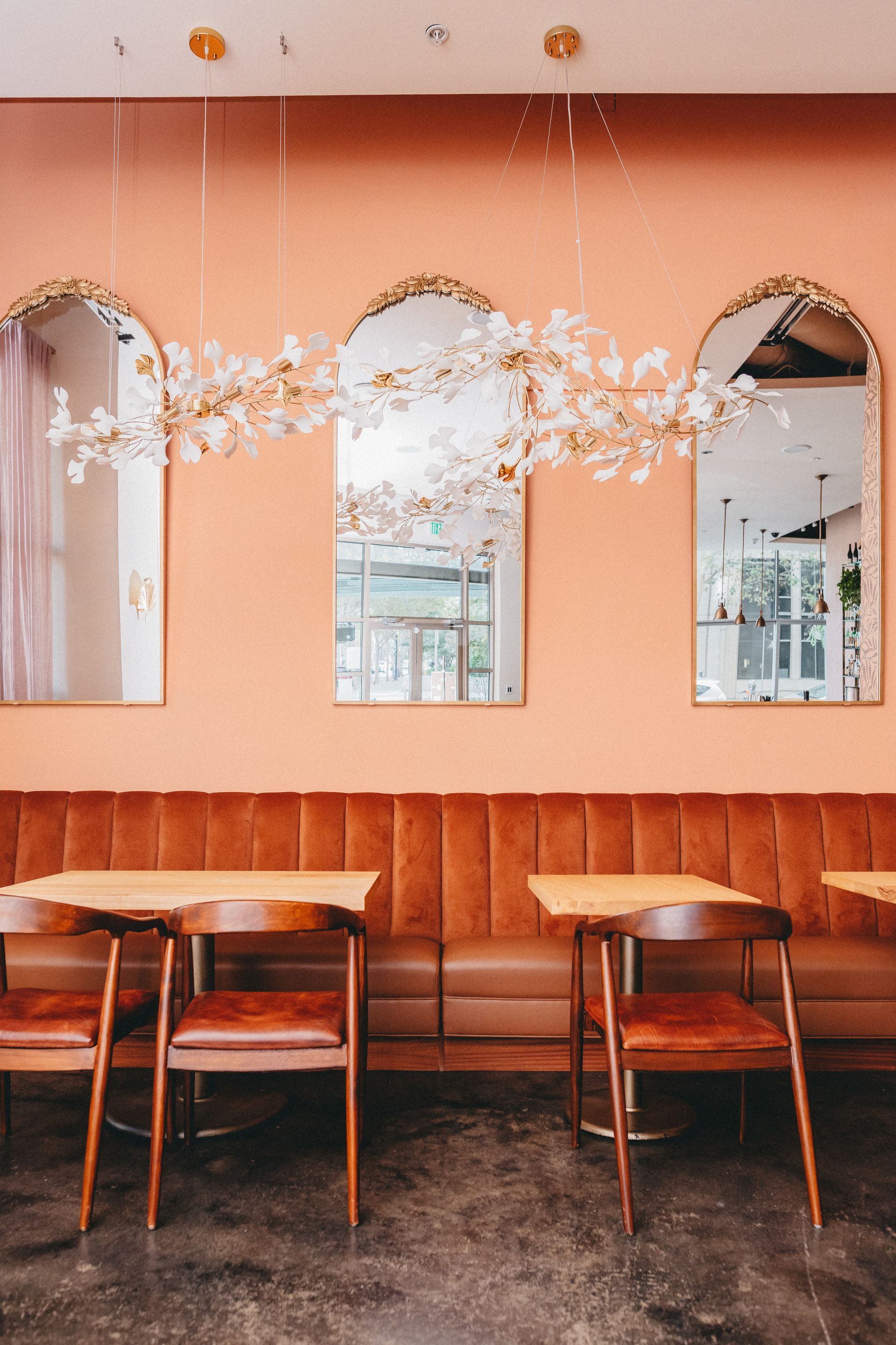 A restaurant with tables and chairs and a pink wall.