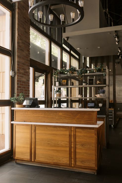 A wooden counter in a restaurant with a chandelier hanging from the ceiling.