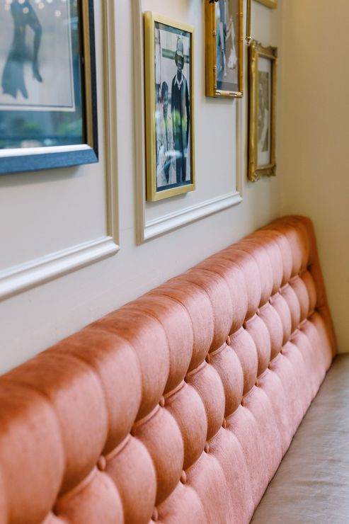 A row of framed pictures hang on a wall above a pink couch