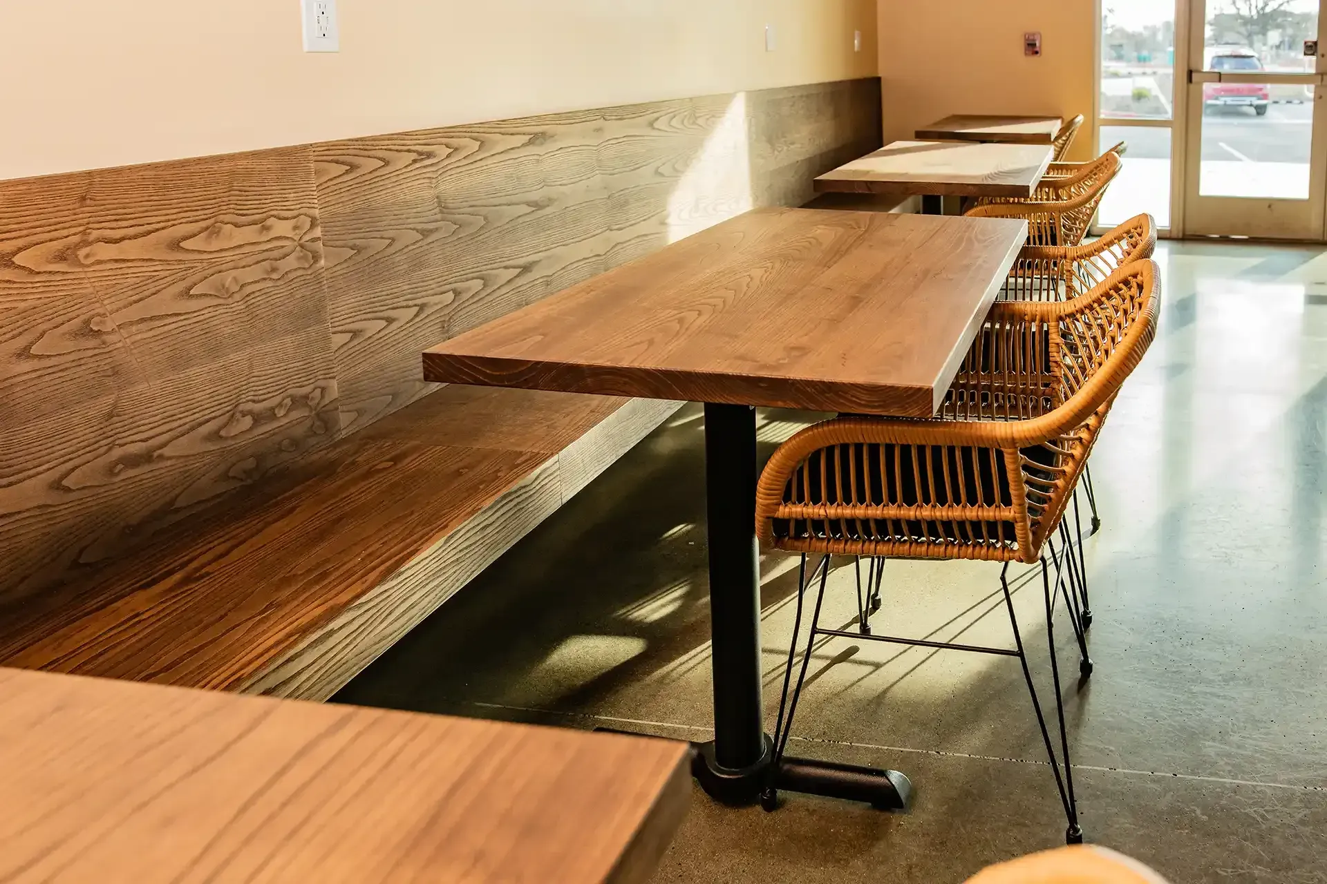 A row of wooden tables and chairs in a restaurant.