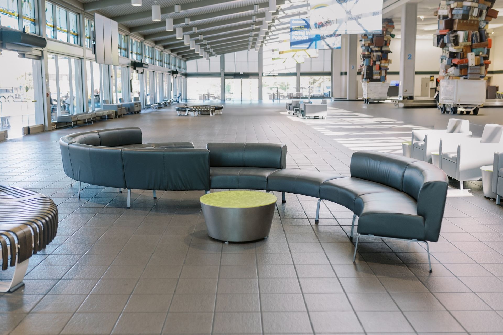 There are a lot of chairs and a table in an airport terminal.