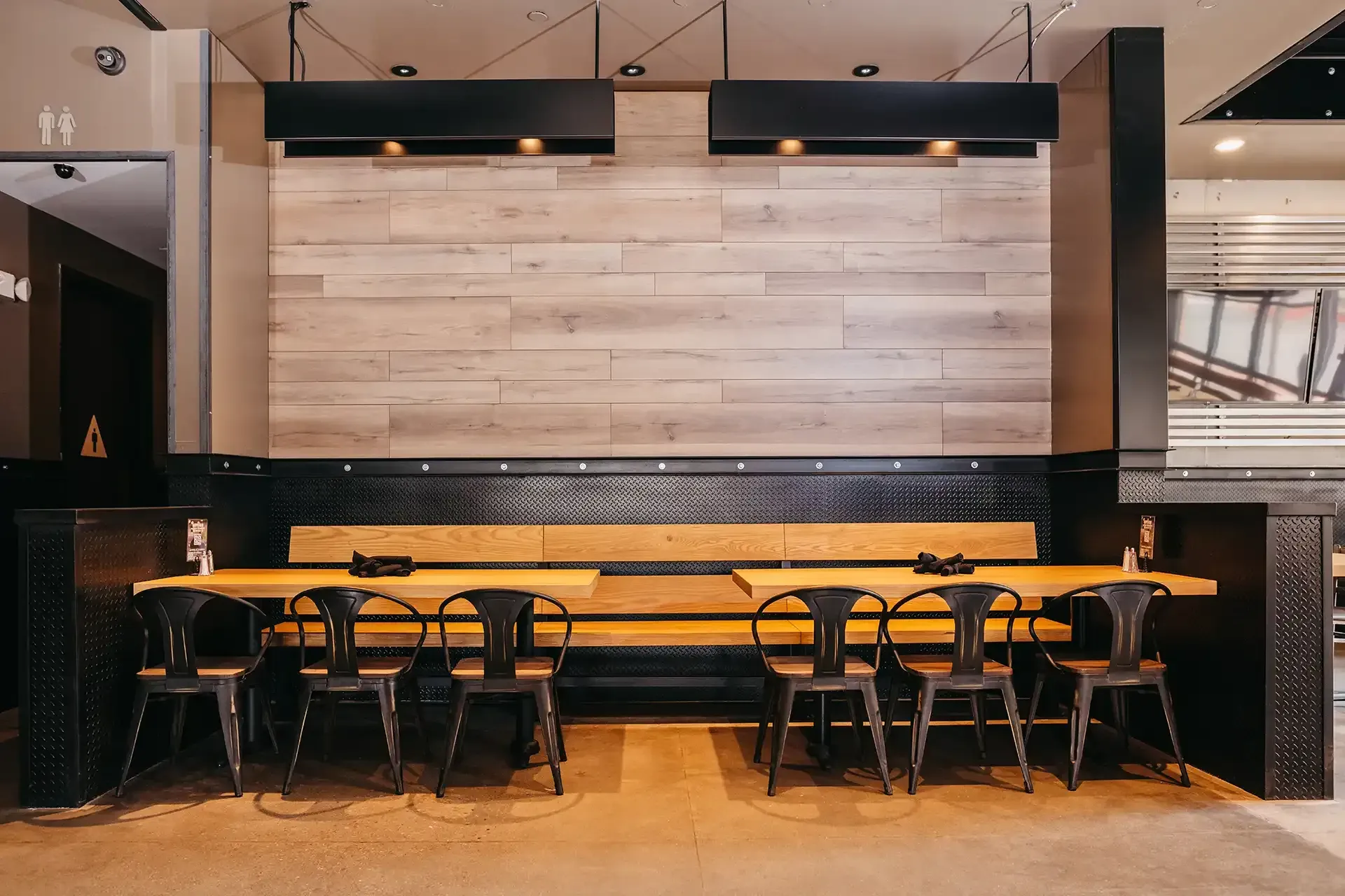 A restaurant with tables and chairs and a wooden wall.