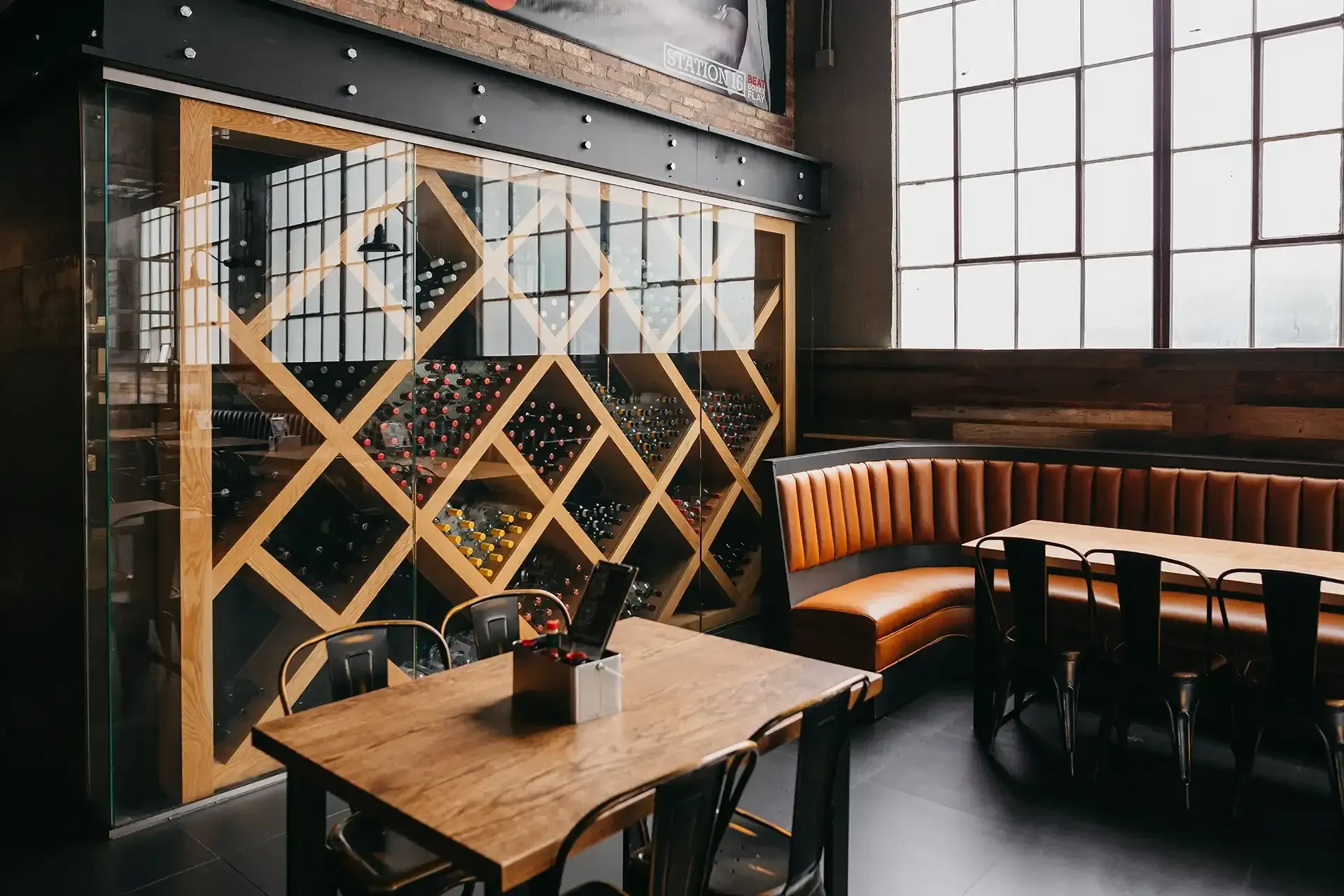 A restaurant with tables and chairs and a wine rack behind them.