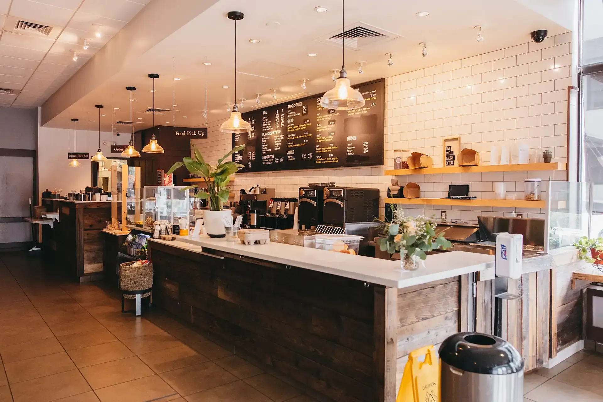 A restaurant with a long counter and a chalkboard on the wall.