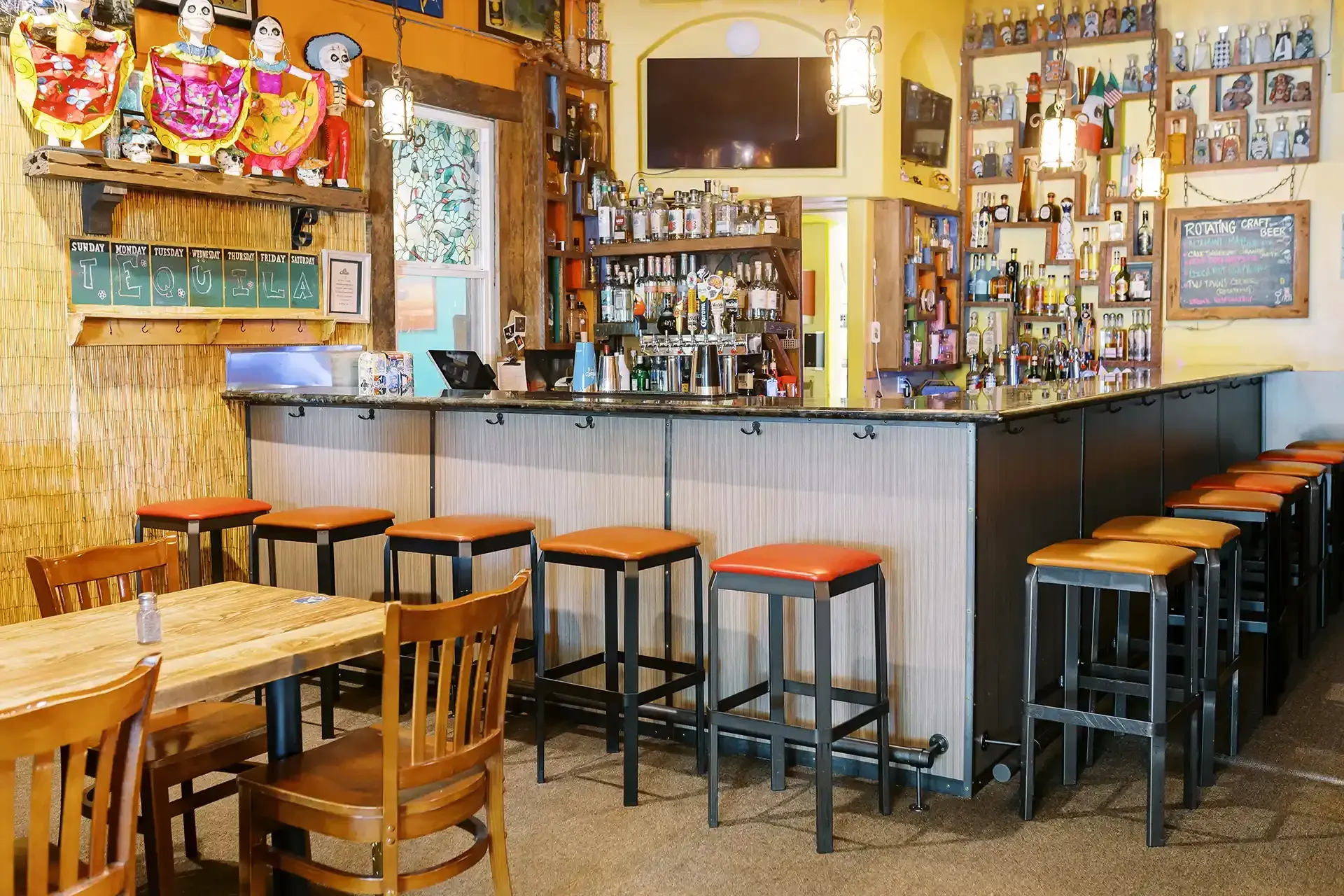 A restaurant with tables and chairs and a long bar.