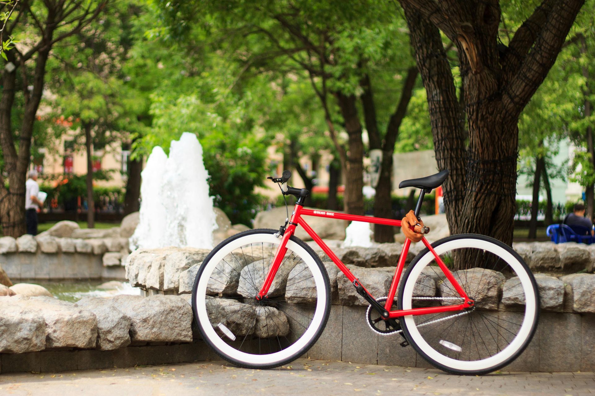 A person riding a red electric fat-tire bike with a grey frame on a sandy beach.