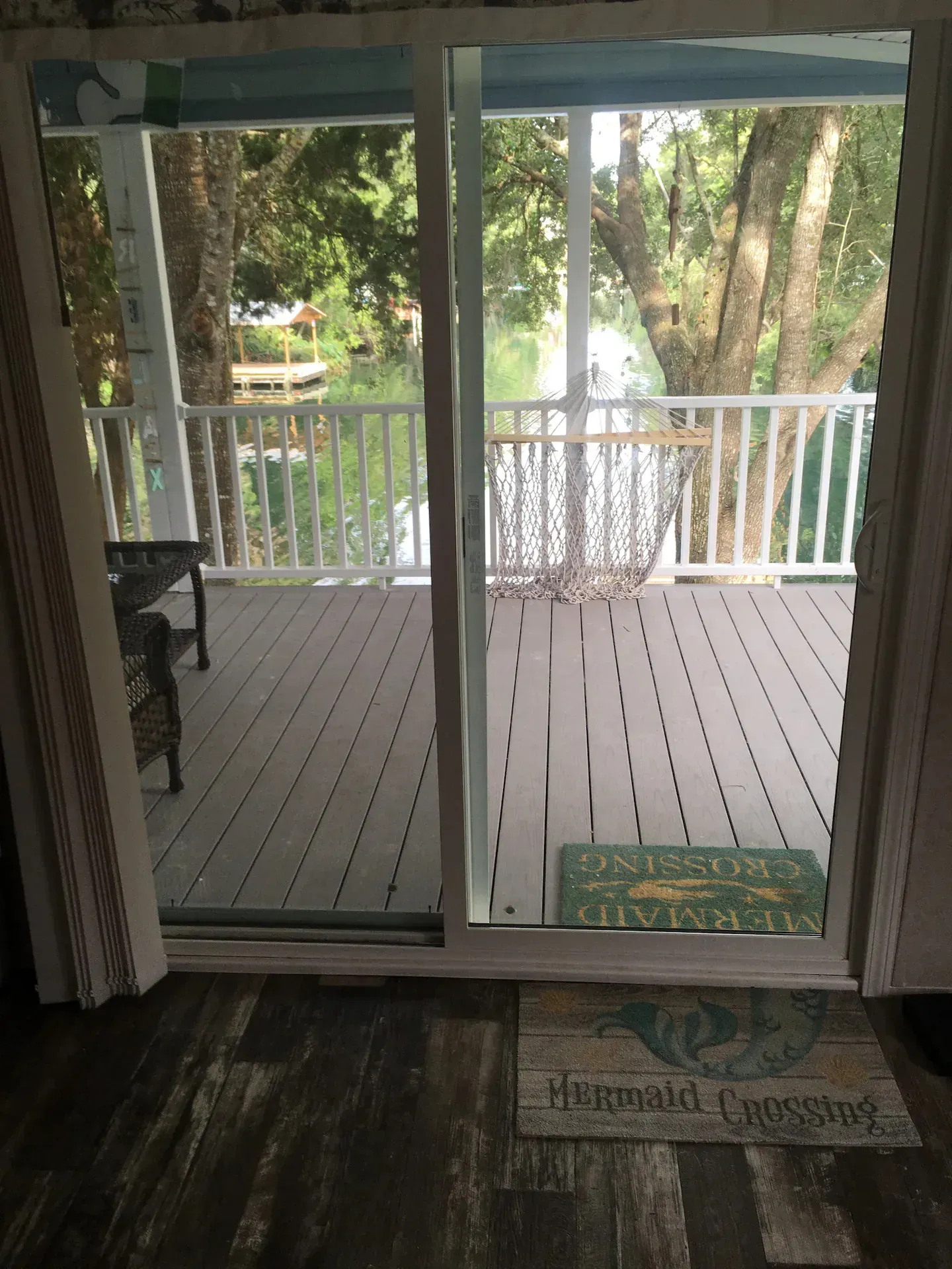 A sliding glass door leading to a porch with trees in the background