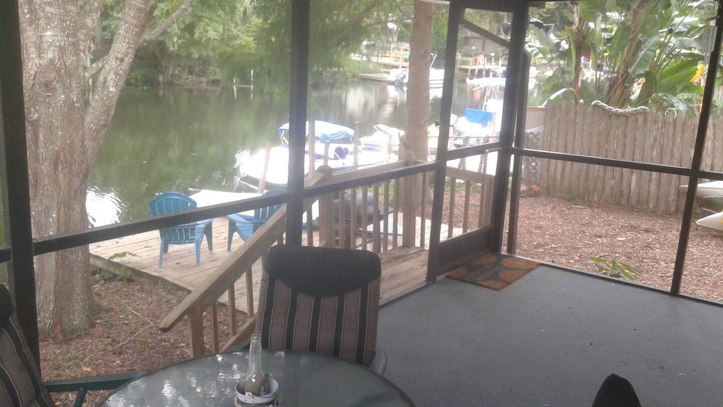 A screened in porch with a table and chairs overlooking a lake.