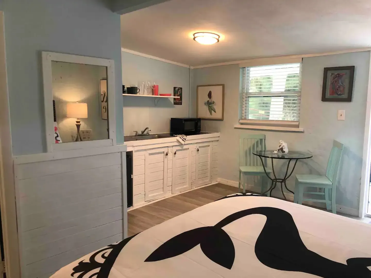 A bedroom with a bed , table , chairs and a mirror.