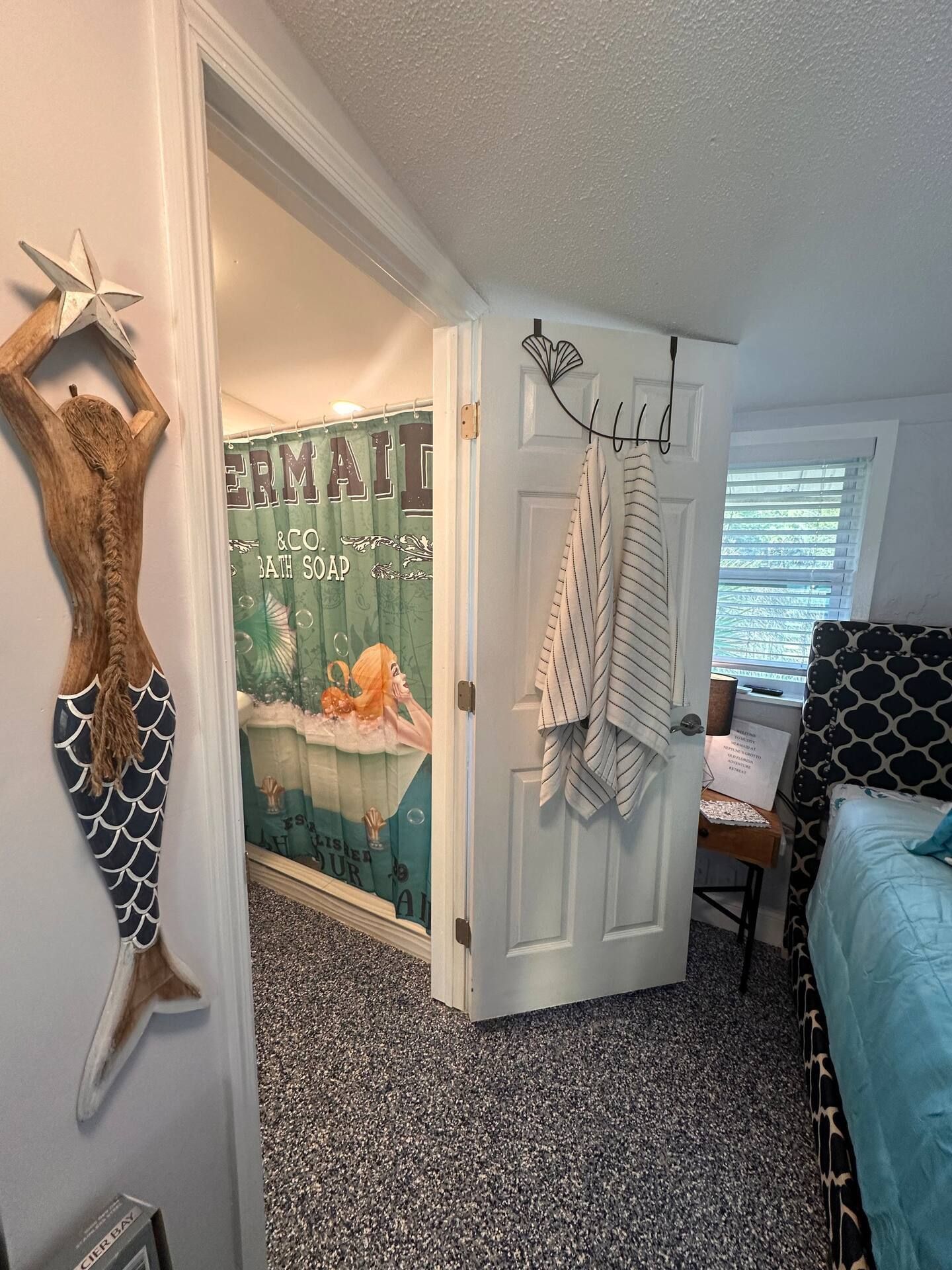 A bedroom with a mermaid statue on the wall and a mermaid shower curtain.