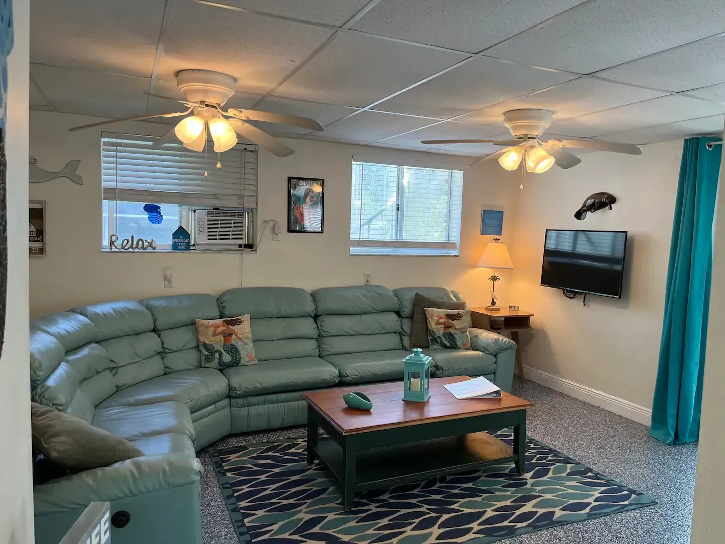 A living room with a sectional couch , coffee table , and ceiling fan.