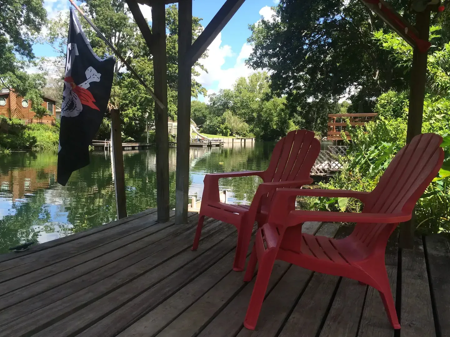 Two red chairs on a deck with a pirate flag hanging from a tree