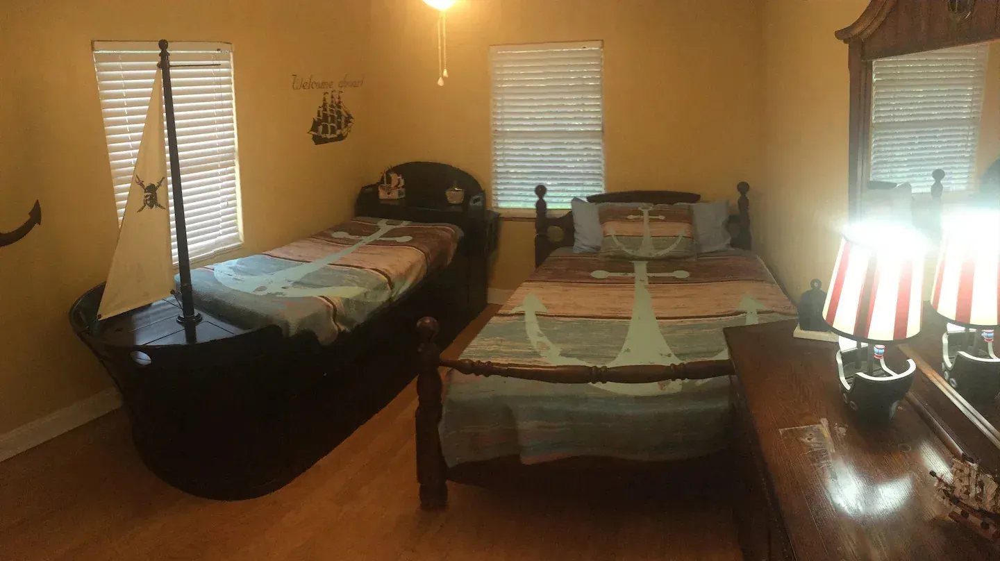 A bedroom with two beds and a pirate ship bed.
