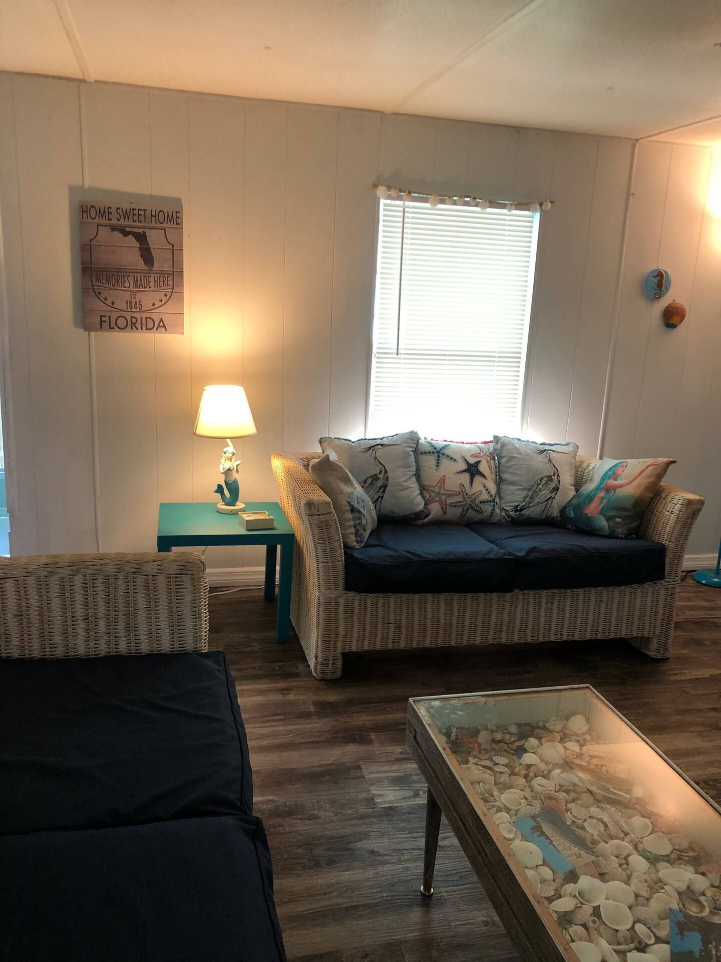 A living room with a couch , table , lamp and window.