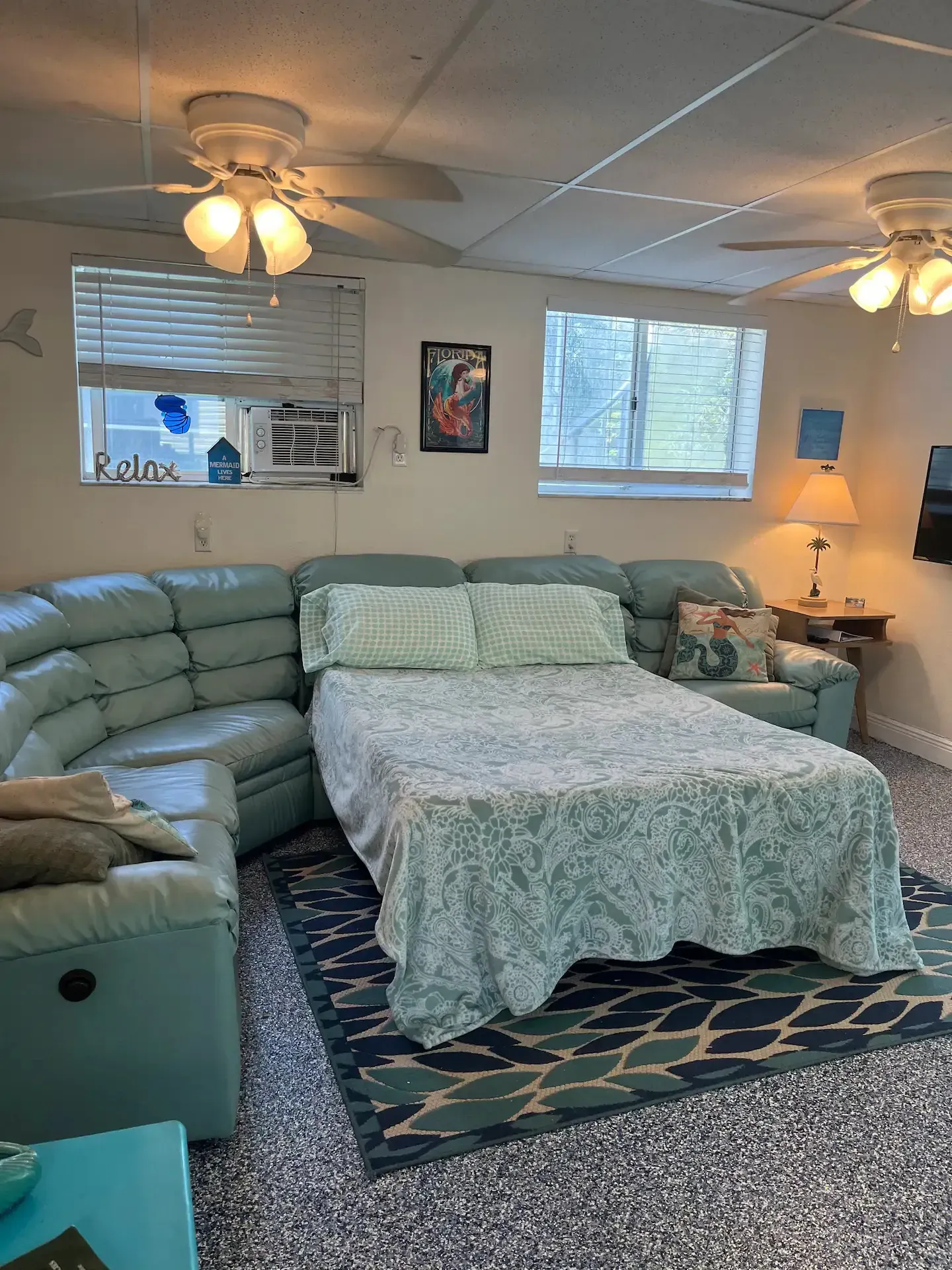 A living room with a bed , couch , and ceiling fan.