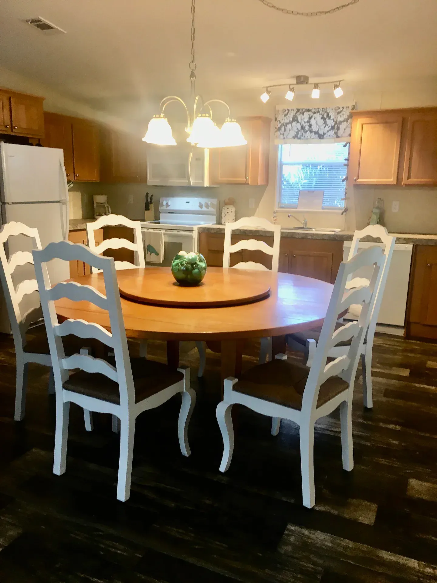 A kitchen with a round table and white chairs