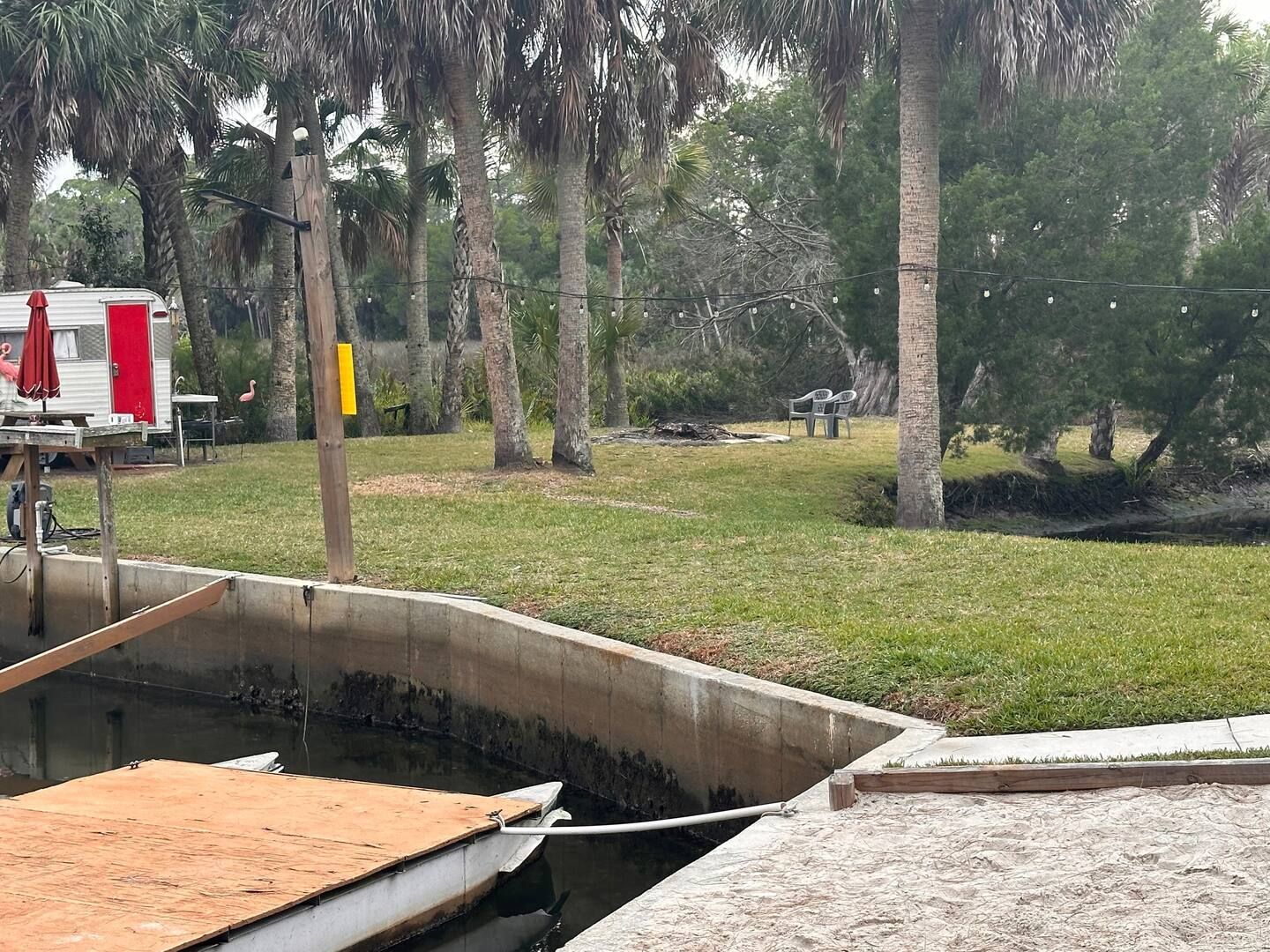 A red and white trailer is parked in a grassy area next to a body of water.