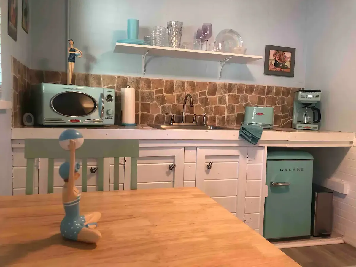 A kitchen with a table , chairs , refrigerator , microwave and sink.
