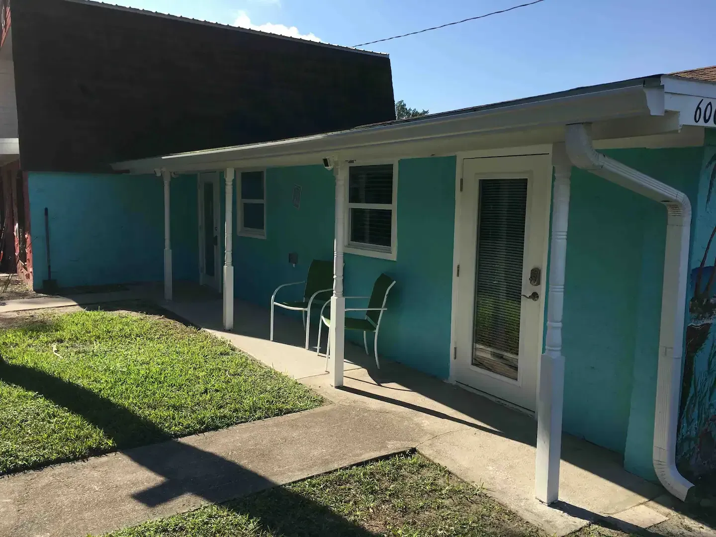 A blue house with a white porch and chairs
