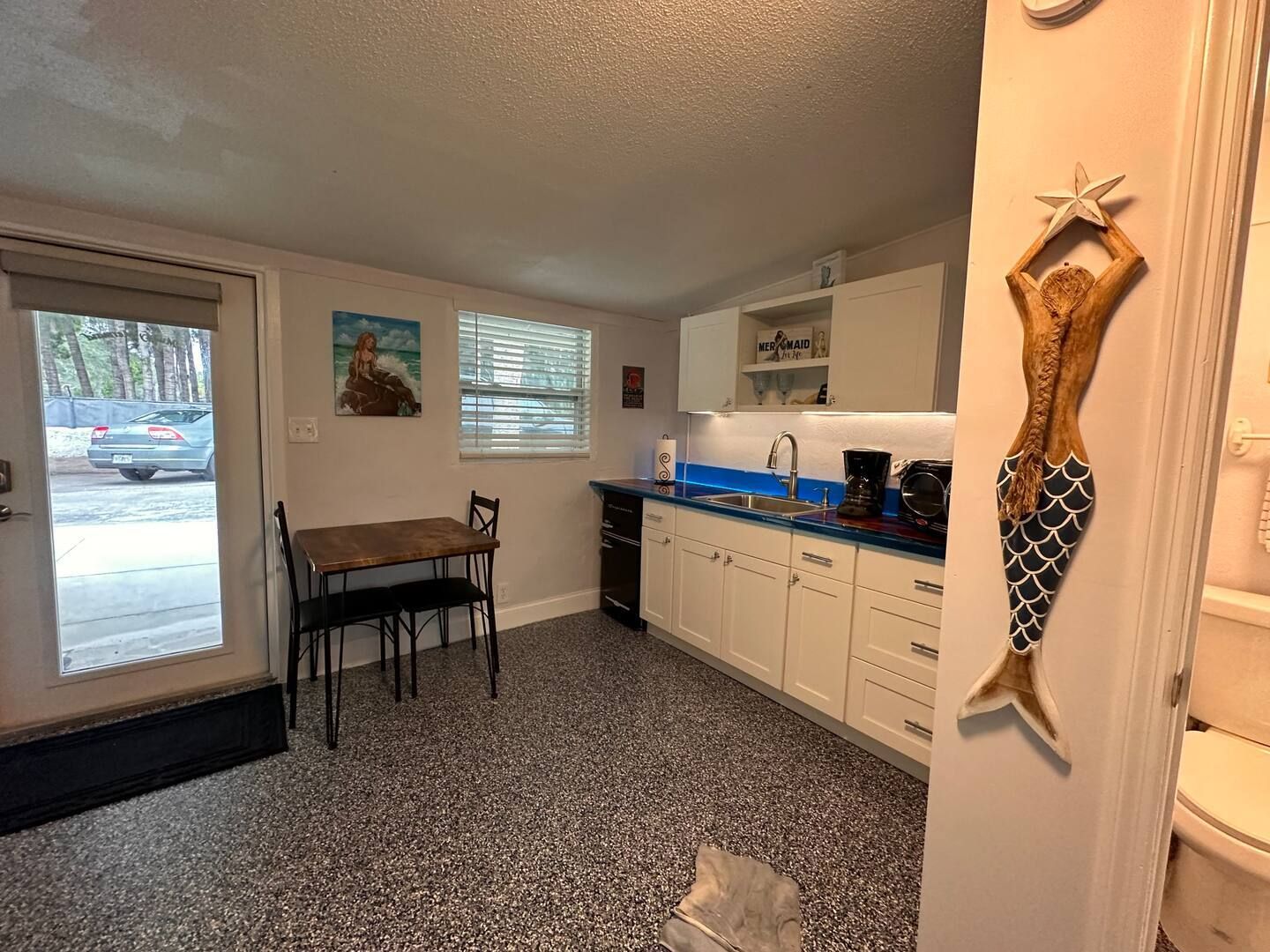 A kitchen with a table and chairs and a mermaid statue on the wall.