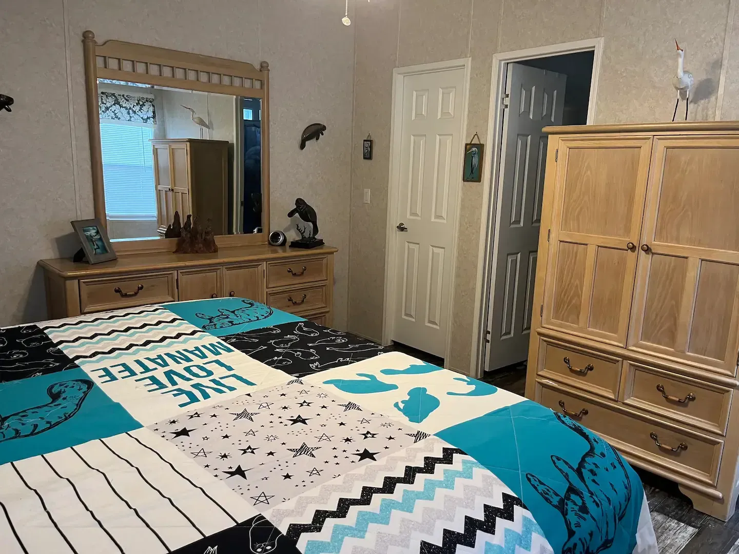 A bedroom with a bed , dresser , mirror and wardrobe