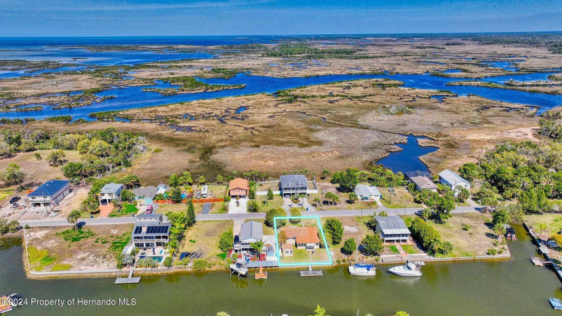 An aerial view of a house on a small island in the middle of a body of water.